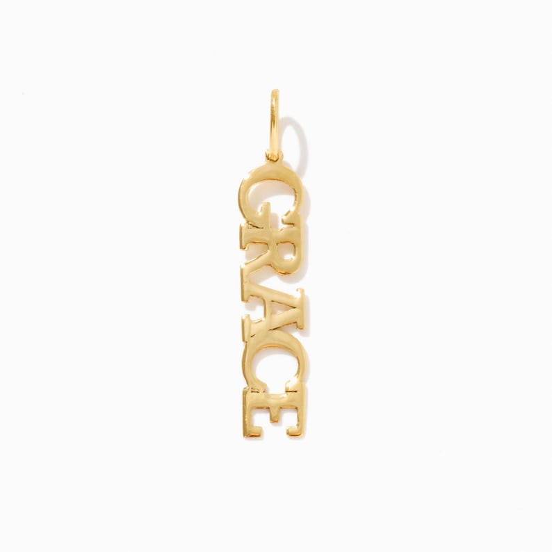 Pode incluir: Colar com pingente de ouro com o nome "GRACE" escrito verticalmente.