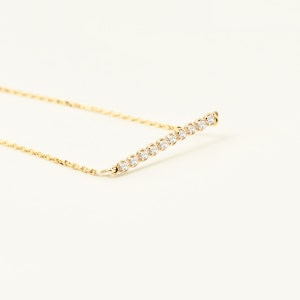 Puede incluir: Un delicado collar de cadena de oro con una fila de pequeños diamantes transparentes dispuestos en línea recta.