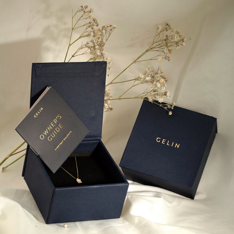 Pode incluir: Uma caixa de joias azul marinho com uma inscri&ccedil;&atilde;o dourada que diz "GELIN" na tampa. A caixa est&aacute; aberta e cont&eacute;m um colar de ouro com um pequeno pingente de diamante. Um pequeno folheto intitulado "OWNER'S GUIDE" &eacute; vis&iacute;vel dentro da caixa.
