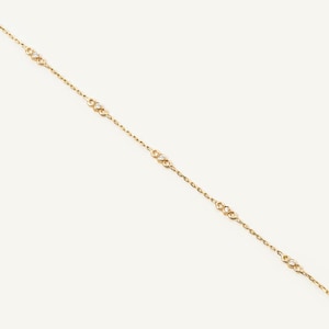 May include: A delicate gold chain necklace with small, clear gemstones spaced evenly along the chain.