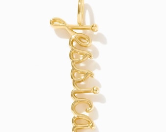 Puede incluir: Un colgante vertical de metal dorado con el nombre Jessica escrito en letra cursiva continua. El diseño incluye una pequeña anilla circular en la parte superior para su sujeción y un acabado pulido que refleja la luz sobre las letras.