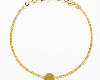 May include: A gold-toned chain bracelet featuring a delicate, thin link design and a single, smooth, circular disc charm centered along the chain. The bracelet includes an adjustable extender chain with larger links and a circular clasp closure.