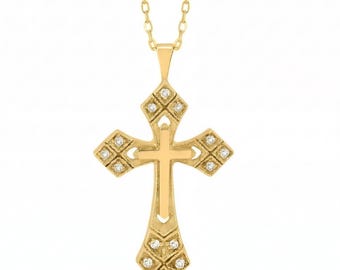 Puede incluir: Un collar con colgante de cruz dorada que presenta una cruz central de oro liso superpuesta sobre un marco de cruz más grande y ornamentado. El marco exterior está decorado con pequeñas piedras claras de corte redondo en cada brazo.