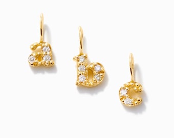 May include: Three gold letter charms shaped as lowercase a, b, and c. Each charm features a textured, beaded surface and is set with small, clear, round-cut stones. Each letter includes a small gold jump ring at the top for attachment.
