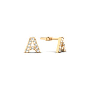 May include: A pair of gold stud earrings shaped like the letter A, featuring a polished gold finish and embedded with small, clear, round-cut white stones along the front surface of each letter, complete with standard post backings.
