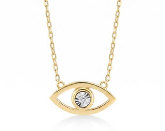 May include: A gold necklace featuring an eye-shaped pendant with a polished metal frame and a central circular setting containing a single, brilliant-cut white gemstone. The pendant is suspended from a delicate, matching gold link chain.