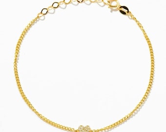 May include: A gold chain bracelet featuring a small, central heart-shaped charm encrusted with tiny clear stones. The bracelet includes a delicate link chain and a circular spring ring clasp at the end, providing a secure and adjustable fit.