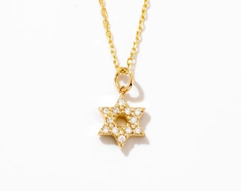 May include: A gold chain necklace featuring a six-pointed Star of David pendant. The pendant is crafted from gold and is encrusted with small, clear, sparkling stones along its entire surface, creating a bright and reflective appearance.