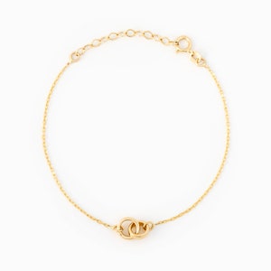 May include: A gold chain bracelet with a double circle charm. The bracelet is made of a delicate chain and has a lobster clasp closure.