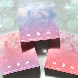 Pode incluir: Três blocos de notas adesivas de cor rosa pastel e azul com um design de nuvens e um gráfico de botão de reprodução. Os blocos têm uma borda branca e um gráfico de botão de reprodução branco com botões de retrocesso e avanço rápido de cada lado.