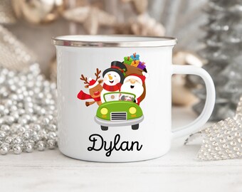 Könnte beinhalten: Weiße Email Tasse mit einer Weihnachtsszene mit Weihnachtsmann, Schneemann und Rentier, die in einem grünen Auto fahren. Die Tasse hat einen silbernen Rand und den Namen "Dylan" unten aufgedruckt.