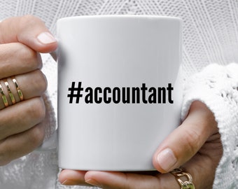 Op de afbeelding: Een witte keramische koffiemok met een zwarte hashtag en het woord "accountant" erop gedrukt.