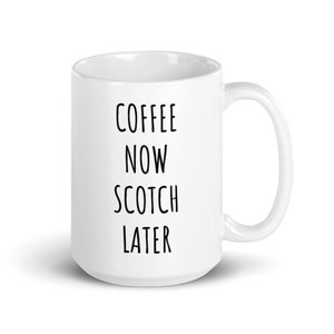 May include: White ceramic coffee mug with the text "COFFEE NOW SCOTCH LATER" in black, vertically aligned. The mug has a curved handle and a glossy finish, suitable for hot beverages. A simple, yet humorous design.