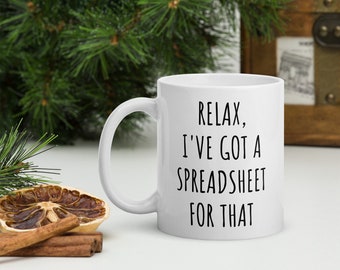 Könnte beinhalten: Eine weiße Keramik-Kaffeetasse mit schwarzem Text, der "Relax, I've got a spreadsheet for that." lautet.
