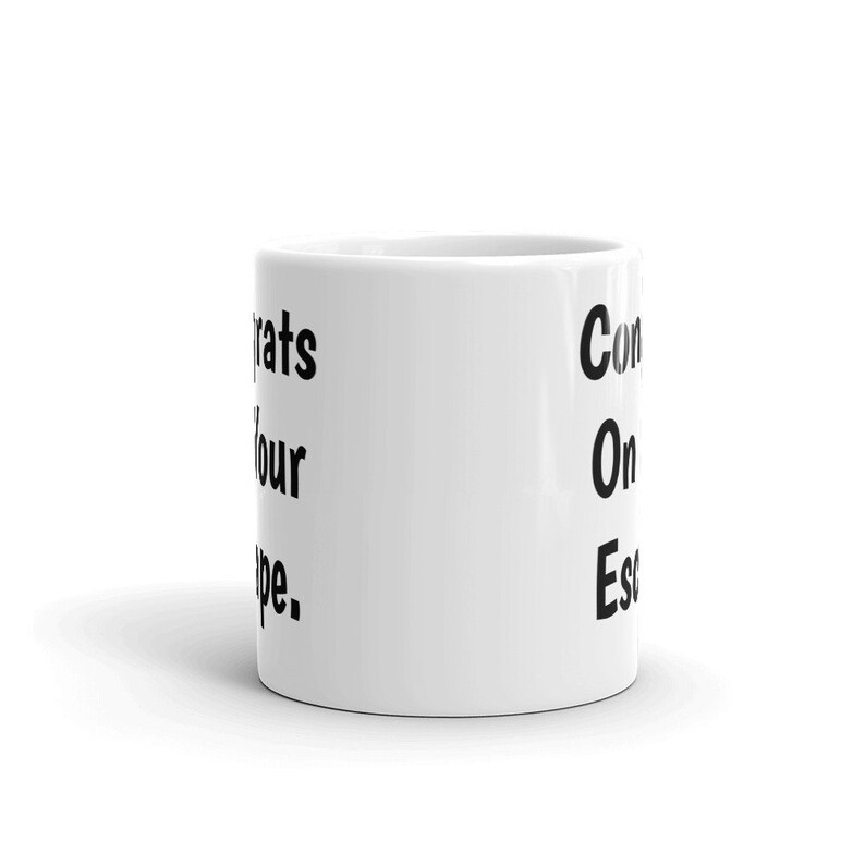 May include: White ceramic mug with black text that reads "Congrats on your escape."