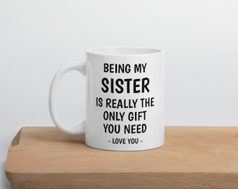 May include: White ceramic coffee mug with black text that reads "Being my sister is really the only gift you need - Love you -"