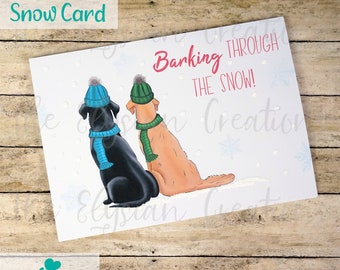 May include: A Christmas card featuring two dogs wearing winter hats and scarves. The dogs are looking up at the snow falling from the sky. The text on the card reads "Barking Through The Snow!"