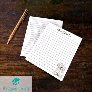 May include: Two white lined notepads with a gold pen on a dark wood surface. One notepad has a dog illustration and the text "Your Text Here". The other notepad has paw prints. The Elysian Creations logo is in the bottom left.