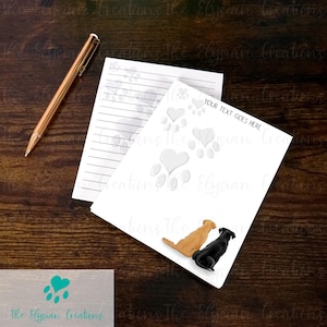 May include: A white notepad with lined paper and a paw print design. The notepad has a space for writing "YOUR TEXT GOES HERE". The notepad features two dogs, one black and one brown, sitting side by side.