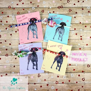 May include: Four Valentine's Day cards featuring a German Shorthaired Pointer dog wearing heart-shaped glasses. Each card has a different message: "You are Paw-some", "Friends - Ever!", "You are dog-gone cute!" and "I woof of you!" Each card has a pencil and a lollipop attached.
