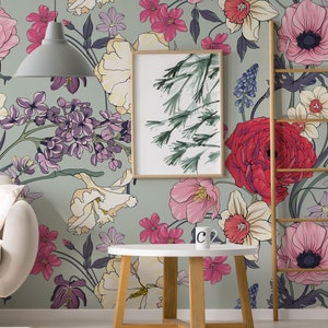 May include: A green floral wallpaper with a variety of flowers in pink, red, white, yellow, and purple. A wooden ladder, a white round table with a wooden base, and a framed print of a green tree are in front of the wallpaper.