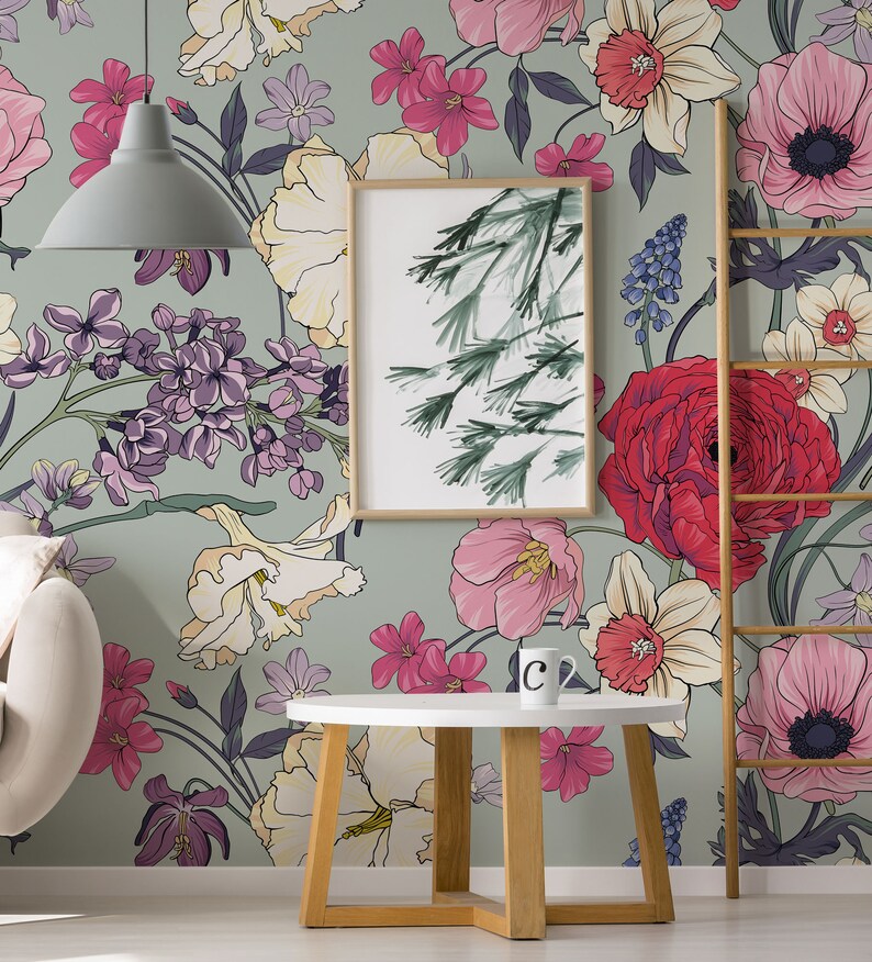 May include: A green floral wallpaper with a variety of flowers in pink, red, white, yellow, and purple. A wooden ladder, a white round table with a wooden base, and a framed print of a green tree are in front of the wallpaper.
