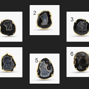 May include: Six unique gemstone rings with gold-colored settings. Each ring features a different black and gray agate stone with a crystal-filled center. The rings are displayed against a white background.