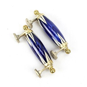 May include: Two blue and white ceramic door handles with gold accents. The handles are oval shaped and have a geometric pattern.