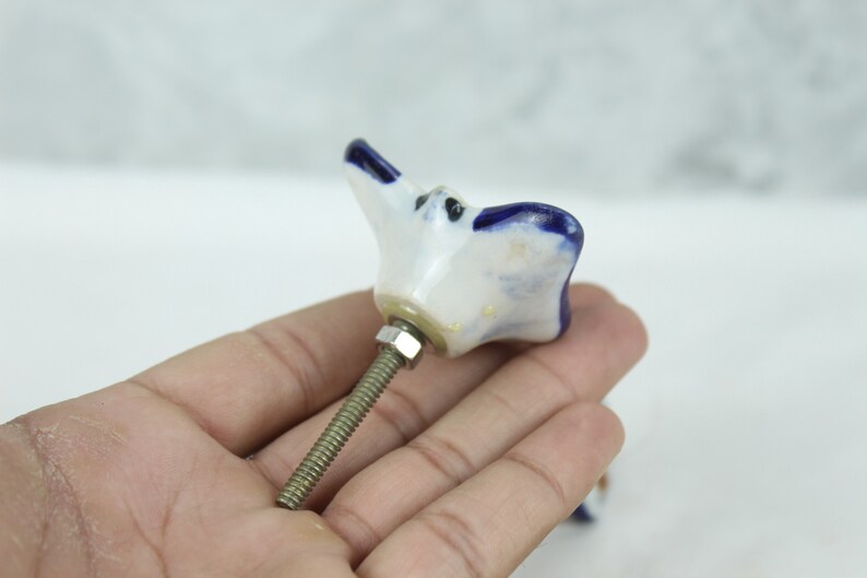 May include: White ceramic cabinet knob with a blue flower design and a silver screw.
