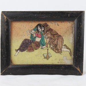 May include: A framed painting depicting a couple in traditional Indian clothing. The woman is wearing a pink and purple outfit, while the man is wearing a brown and green outfit. They are sitting on a yellow background.