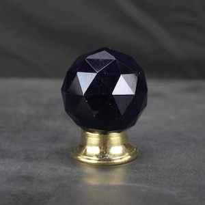 May include: A dark blue crystal cabinet knob with a faceted design and a gold base.