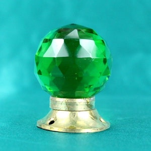 May include: A green glass door knob with a faceted design and a brass base.