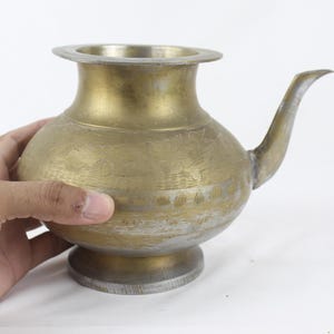 Pode incluir: Uma chaleira de latão com um design ornamentado e um bico. A chaleira tem um corpo redondo e uma base larga.