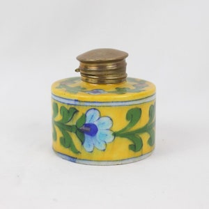 May include: A small yellow ceramic jar with a brass lid. The jar is decorated with a blue and green floral pattern.