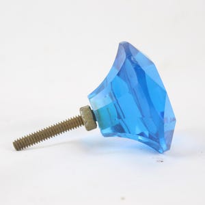 May include: A blue glass cabinet knob shaped like a diamond with a silver screw.