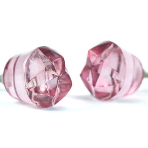 May include: Two pink glass cabinet knobs with a faceted design and silver screws.