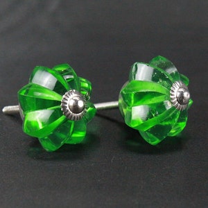 May include: Two green glass cabinet knobs with a silver metal base. The knobs have a fluted design and are perfect for adding a touch of vintage charm to any home.