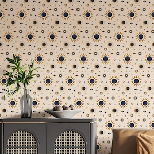 May include: A beige wallpaper with a repeating pattern of navy blue and gold suns. The wallpaper is in a living room with a brown leather sofa, a black cabinet, and a black and white rug.
