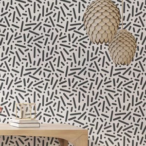 May include: A wooden table with a white background featuring a black and white geometric pattern. The table has a simple, modern design with rounded edges.