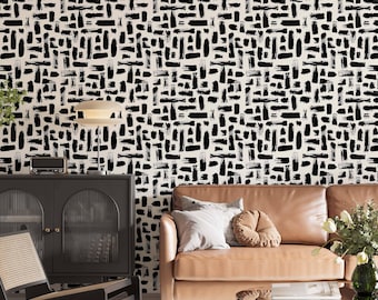 May include: A living room interior with a black and white geometric patterned wallpaper, a brown leather sofa with pillows, a black chair with a woven seat, a black cabinet with glass doors, a glass coffee table, and a wooden pedestal with a plant.