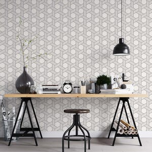 May include: A black and white geometric wallpaper pattern with a wooden desk, black metal trestle legs, a black metal stool, and a black pendant light hanging from the ceiling.