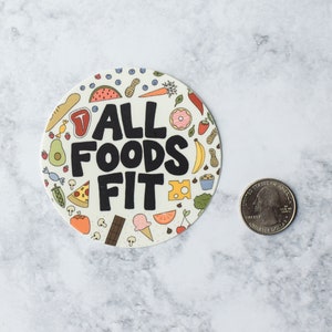 K&ouml;nnte beinhalten: Ein runder Aufkleber mit wei&szlig;em Hintergrund und bunten Illustrationen verschiedener Lebensmittel. Der Text "ALL FOODS FIT" ist in schwarzen Buchstaben gedruckt.