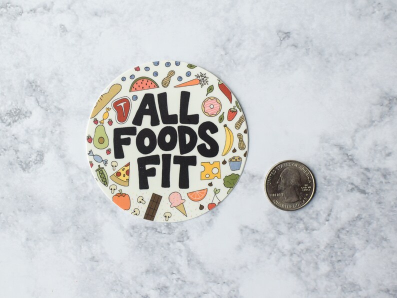 K&ouml;nnte beinhalten: Ein runder Aufkleber mit wei&szlig;em Hintergrund und bunten Illustrationen verschiedener Lebensmittel. Der Text "ALL FOODS FIT" ist in schwarzen Buchstaben gedruckt.