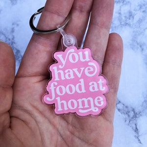 May include: Pink acrylic keychain with the text "You have food at home" in white lettering.