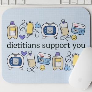 May include: A blue mouse pad with a light blue background and a white grid pattern. The mouse pad features a variety of colorful cartoon images of medical equipment, including IV bags, pumps, and syringes. The text "dietitians support you" is printed in black at the bottom of the mouse pad.