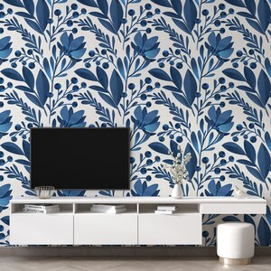 May include: A white media console with three drawers and a flat screen TV on top. The wall behind the console is covered in blue and white floral wallpaper.