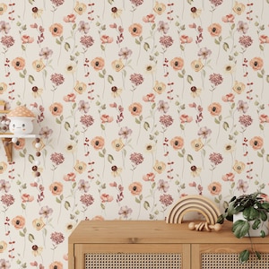 May include: Wallpaper with a repeating pattern of watercolour flowers in orange, yellow, and purple, with green stems and leaves on a cream backdrop. A wooden cabinet, a wooden rainbow, and a potted plant are in the foreground.