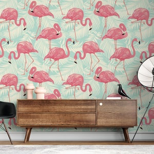 May include: A room with a flamingo-themed wallpaper. The wallpaper features pink flamingos and green palm leaves on a light blue background. A wooden cabinet, black chair, and a floor lamp are in the room.