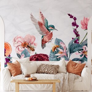 May include: Watercolor mural featuring a vibrant hummingbird with outstretched wings, surrounded by pink flowers, bees, and lush green foliage. The design includes a slice of orange and a variety of purple and red floral elements, creating a botanical theme.