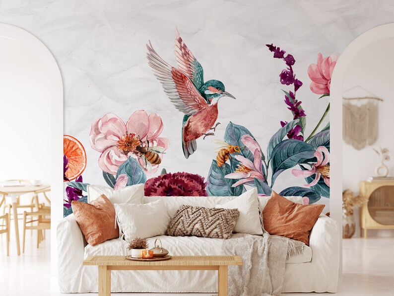May include: Watercolor mural featuring a vibrant hummingbird with outstretched wings, surrounded by pink flowers, bees, and lush green foliage. The design includes a slice of orange and a variety of purple and red floral elements, creating a botanical theme.